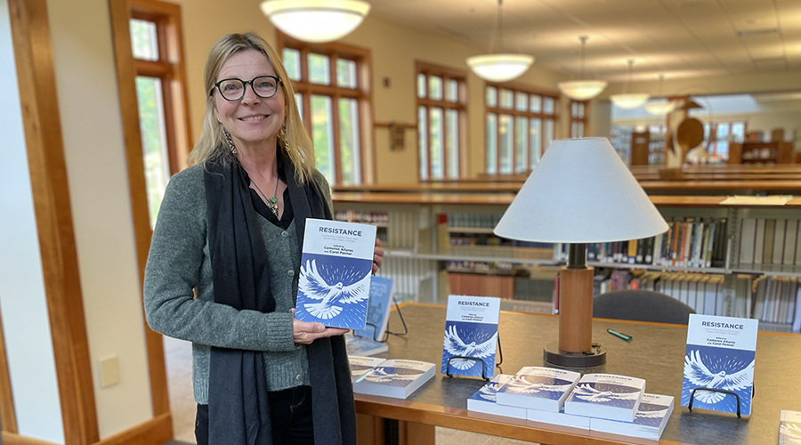 Cameron Altaras, PhD, holds a copy of the book, Resistance, at a book celebration event in the AMBS Library.