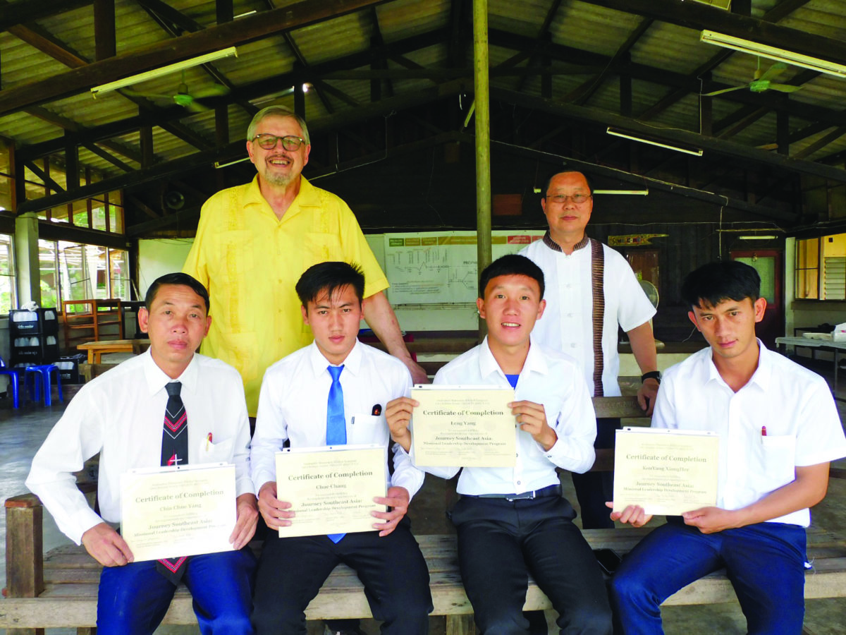 Group of four students hold their certificates of completion in front of two instructors