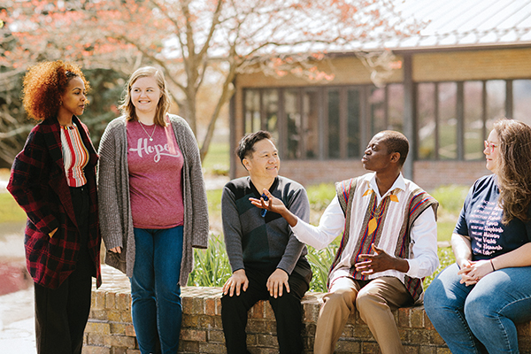 Students converse in the AMBS courtyard in 2023: Misgana Alemayehu Eshete of Ethiopia, Amy Marshall of Ohio, Pornchai (Paul) Banchasawan of Thailand, Daniel Teye Nuertey of Ghana and Debbie Bledsoe of North Carolina. (Credit: Brittany Purlee/AMBS)