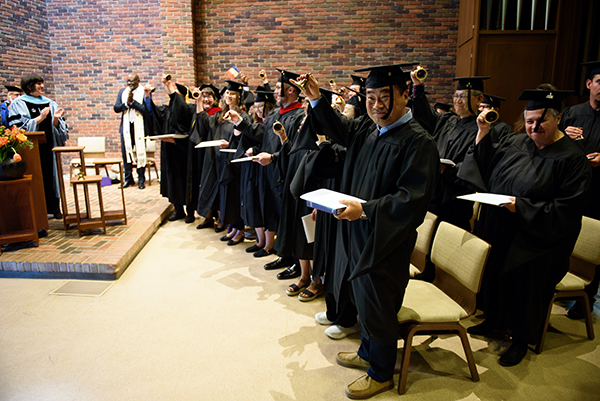 The members of the Class of 2026 who were present in person for Anabaptist Mennonite Biblical Seminary’s May 2 Commencement Service and eight students who are part of a Korean-language master’s-degree cohort ring their bells in celebration. The brass bells are replicas of the bell that rings on the seminary campus. At left are David Boshart, PhD, AMBS President; Beverly Lapp, EdD, AMBS Vice President and Academic Dean; and Rev. Leonard Dow, commencement speaker. (Credit: Jason Bryant/AMBS)